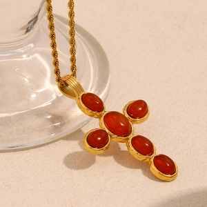 Macro shot of 18K gold plated cross pendant necklace set with five red gemstones