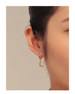 Close-up of elegant gold crescent moon earrings with cubic zirconia worn by a model