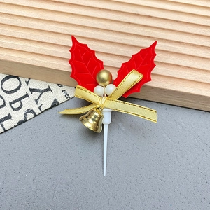 Detail of Christmas cake topper with holly leaves, red bow, and golden bell ornaments