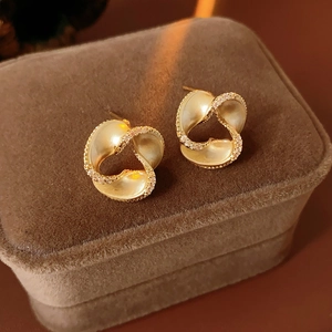 Detailed close-up of golden spiral earrings with diamonds on brown velvet box