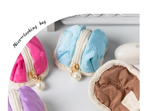 Detail of mini quilted zipper pouches with pearl charm and wavy stitching textures