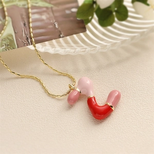 Détail du collier avec pendentif tube en émail rose et rouge et chaîne à billes dorée