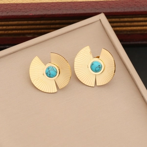 Golden fan-shaped earrings with turquoise stones on a beige jewelry display pad