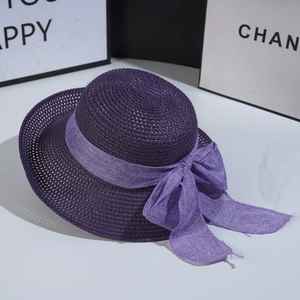 Detail of deep purple woven straw hat featuring a large decorative lavender linen bow