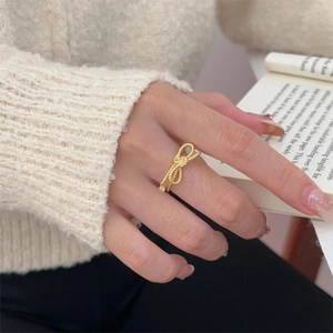 Elegant gold bow ring with twisted band and single zircon worn on hand in cozy setting