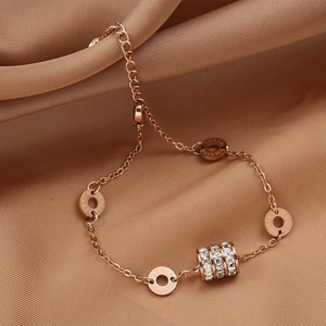 Macro detail of rose gold double-layer chain bracelet with zircon and engraved charms