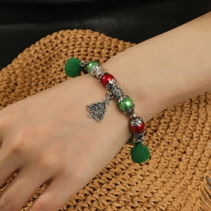 Bracelet de Noël avec perles rouges vertes et pendentif sapin en argent sur le poignet