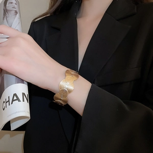 Detailed view of wide gold cuff bracelet featuring geometric spiral texture on model