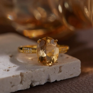 Macro shot of an oval yellow citrine sterling silver ring on a beige stone base