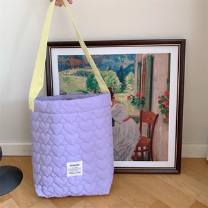 Detail of purple heart-quilted fabric tote bag with contrasting bright yellow handles