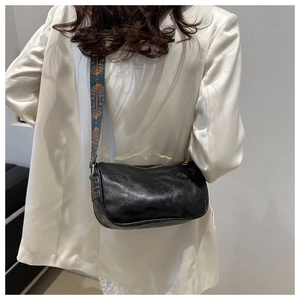 Detail of black leather Boston bag with bohemian ethnic patterned wide shoulder strap