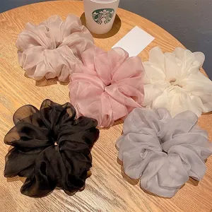 Detailed set of five organza scrunchies in pastel colors on a wooden surface