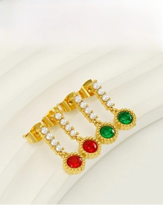 Detail of vintage 18K gold-plated emerald and pearl earrings on a white textured background