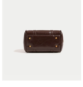 Detailed macro view of dark coffee leather boston bag bottom with gold metal studs