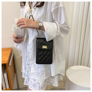 Detail of black quilted chain phone bag with gold twist lock on floral dress