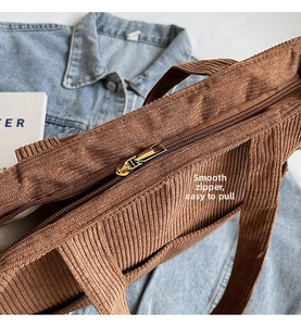 Detail of the high-quality gold metal zipper on a brown corduroy tote bag with lining