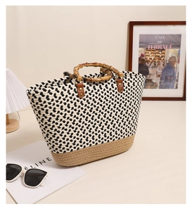 Detail of woven straw bag showing bamboo top handles and black-white pattern texture