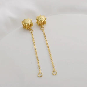Detailed close-up of matte gold sun smiley face earrings with long elegant chain tassels