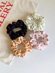 Close-up of four floral chiffon hair scrunchies with elegant bow ribbon details