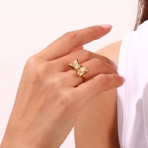 Close-up of 18K gold plated stainless steel bow ring with micro-set diamonds on finger