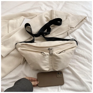 Detail of off-white crossbody chest bag showing three zipper pockets and black wide strap