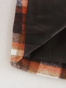 Detailed macro view showing orange plaid fabric and silky black inner lining of the blazer
