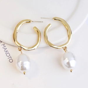 Detailed close-up of baroque pearl earrings with irregular gold rings and S925 silver studs