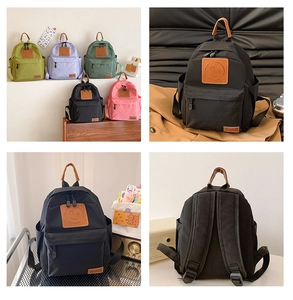 Detail of multi-color canvas kids backpacks with leather smile logo and front pocket