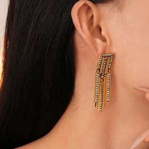Close-up of long gold fringe earrings with rhinestones on model showing jewelry detail