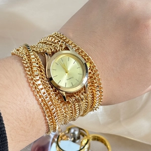 Close-up of golden multi-strand chain bracelet watch with a round quartz dial on wrist