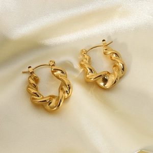 Detailed view of gold plated stainless steel twisted hoop earrings on silk fabric