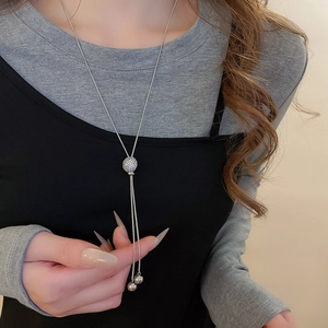 Detail of silver snake chain necklace with zircon-studded slider and tassel pendants
