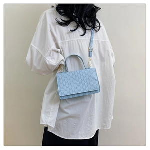 Side view of light blue printed crossbody bag with M-pattern texture on a female model