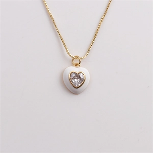 Detail of a gold heart pendant with white enamel and a sparkling heart zircon center