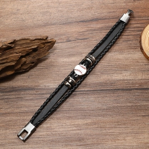 Detailed view of handmade multilayer braided leather bracelet with baseball charm on wood