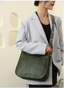 Close-up of dark green PU leather tote bag with a trendy leopard print wide shoulder strap