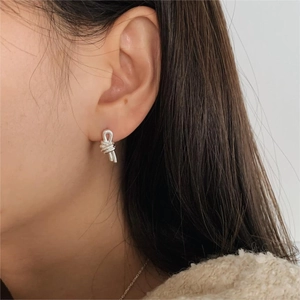 Minimalist 925 sterling silver knotted stud earring worn by model on beige background