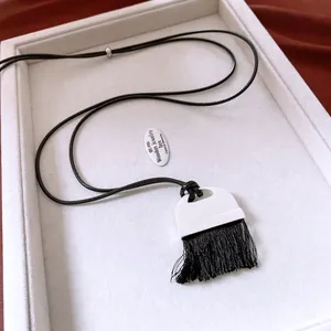 Detail view of a vintage leather tassel necklace with a black and white contrast pendant