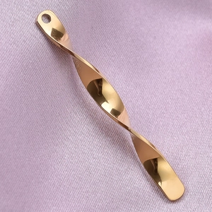 Macro detail of twisted rose gold stainless steel pendant on textured purple fabric