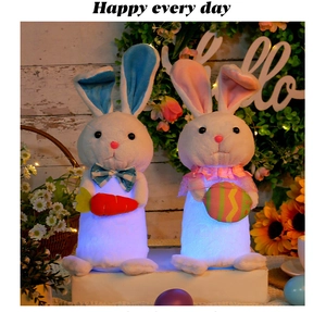 Detail of two glowing Easter bunny plushies with LED lights holding a carrot and colorful egg