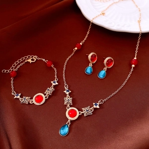 Detail view of vintage jewelry set with red and blue resin teardrop pendants on silk