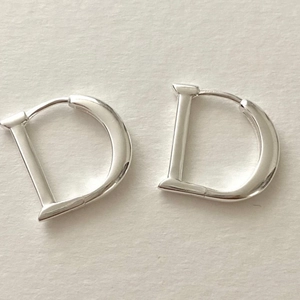 Polished S925 sterling silver D-shaped hoop earrings on minimalist textured background