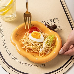 Creative pumpkin-shaped yellow ceramic plate for pasta and salad with a warm dining scene