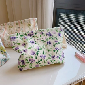 Close-up of three floral cotton makeup bags with simple wish labels and zipper closure