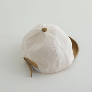 Detail view of cotton baby baseball cap with beige crown and adjustable velcro strap