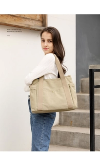 Detail of khaki canvas tote bag showing reasonable storage and multiple pockets on model