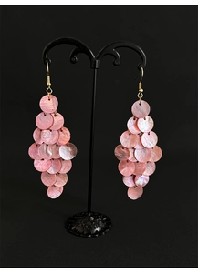 Detailed view of pink shell tassel earrings with gold hooks on a black display stand