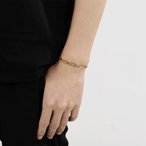 Close-up of a minimalist gold hollow link chain bracelet worn on a model's wrist