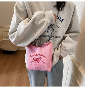 Close-up of pink nylon crossbody bag with red cherry embroidery and checkered straps