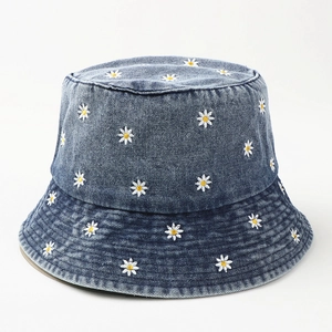 Detailed close-up of small white daisy embroidery on dark blue washed denim bucket hat
